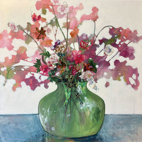 Green glass vase with display of pink flowers on a blue table.