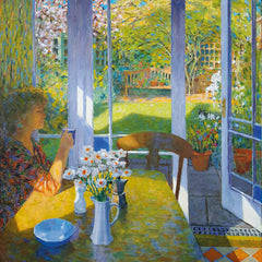 Art greeting card by Patrick Cullen. Woman sitting at a kitchen table, drinking tea in a conservatory with spring flowers in a vase and a sunny view of the garden with a dog.