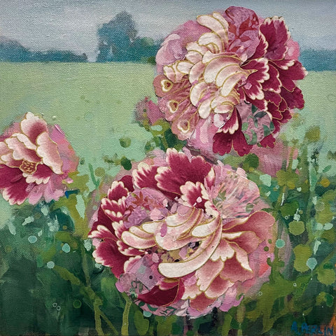 Large, pink, blousy Peonies in foreground with green field behind.