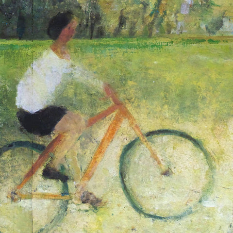 Person on an orange bike, cycling through a meadow with trees in the background.