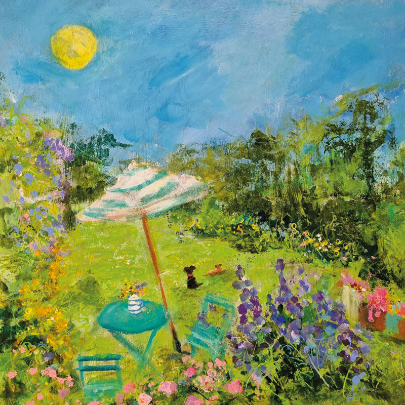 Sunny garden with table and chairs and umbrella. Small black dog sitting on the grass.