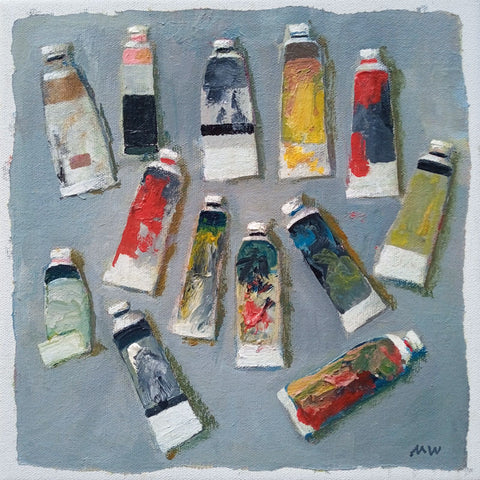 Tubes of different coloured oil paints on a grey background.
