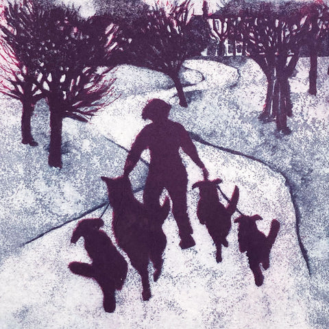 Silhouette of a person walking down a path with four dogs on leads. 